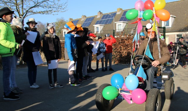 De jubilerende meester Alfons wordt feestelijk onthaald op het schoolplein.