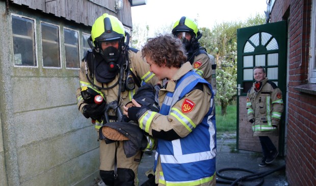 Kinderburgemeester Hessel helpt brandweerlieden een 'slachtoffer' in veiligheid te brengen.