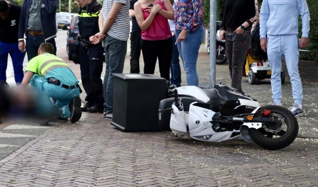 De scooter viel door de botsing op de grond.