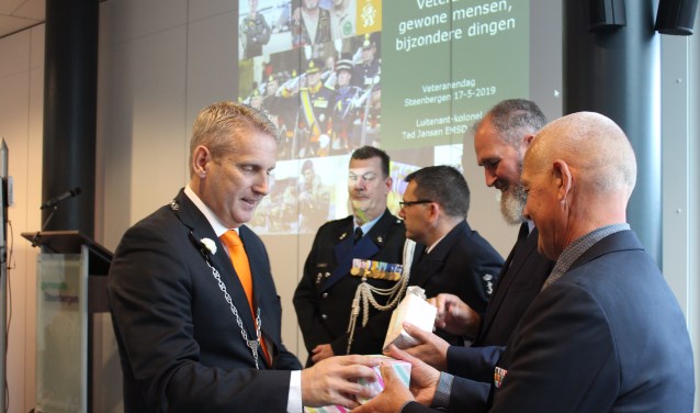 Burgemeester Van den Belt deelt een glasgeschenk uit aan bestuursleden van Veteranen Steenbergen (VEST)