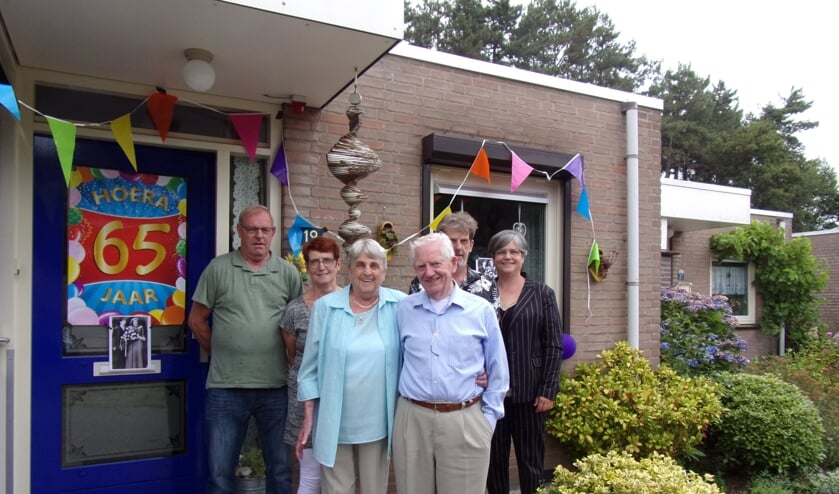 Jef en Virginia Scheffers bij hun vrolijk versierde voordeur, omringd door hun kinderen en aanhang.