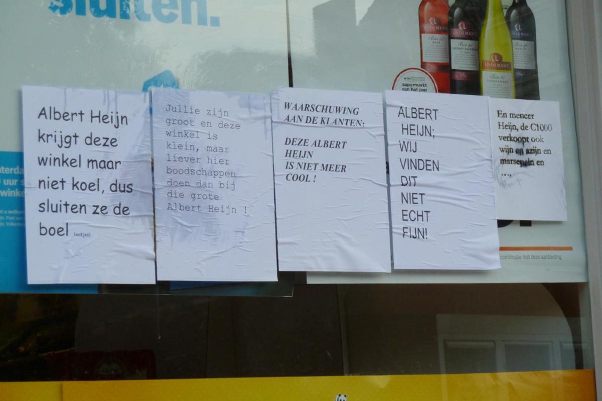 De AH aan de Flierstraat is beplakt met teksten door boze buurtbewoners. Ze zijn boos vanwege de sluiting. foto Perry Roovers