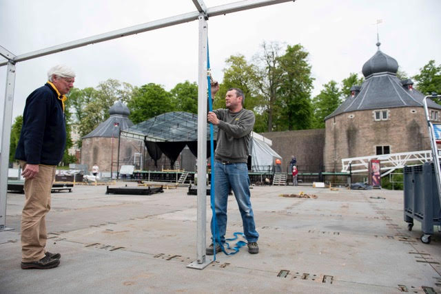 De festivaldirecteur kijkt toe hoe een medewerker een tent opbouwt