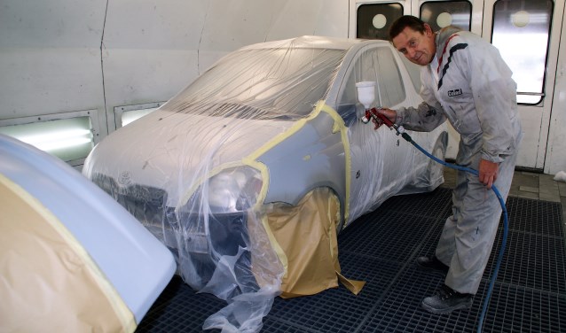 Medewerker Harry Bosman aan het werk in de spuitcabine van Delft Autoschade.