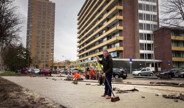 Ondernemer Martin Panis veegt, symbolisch, het laatste stukje van de nieuwe parkeerplaatsen in.
