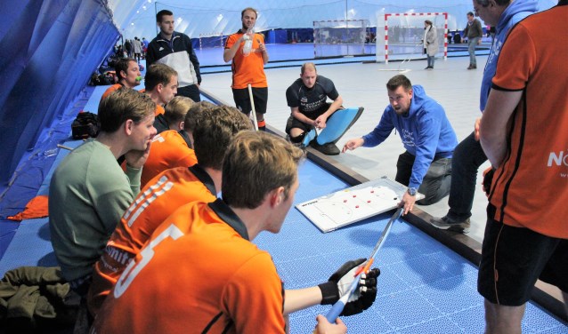 De spelers van De IJssel luisteren aandachtig naar de instructies van coach Mathieu de Jong. (archieffoto)