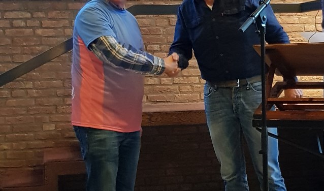 Koorlid Leendert Tanis (links) ontvangt een FietsJeMans-shirt uit handen van dirigent Martin Mans. (foto: pr)