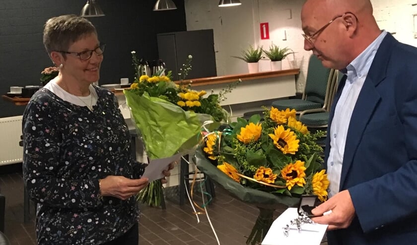 Zonnebloemen en een gouden speld voor Zonnebloemvrijwilliger Rinie van de Nouweland.