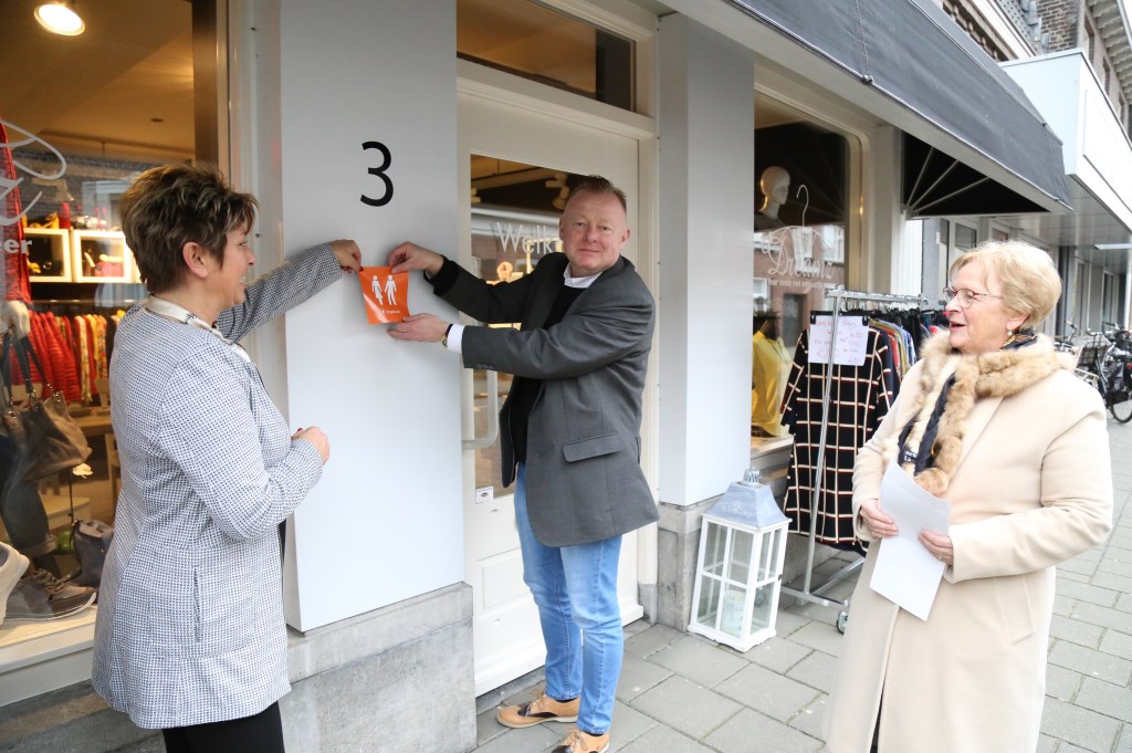 Ondernemer Petra Essen (l.), wethouder Eric van den Broek en Diny Stolvoort plakken de eerste 'Hoge Nood' sticker. | Fotonummer: b55bf9
