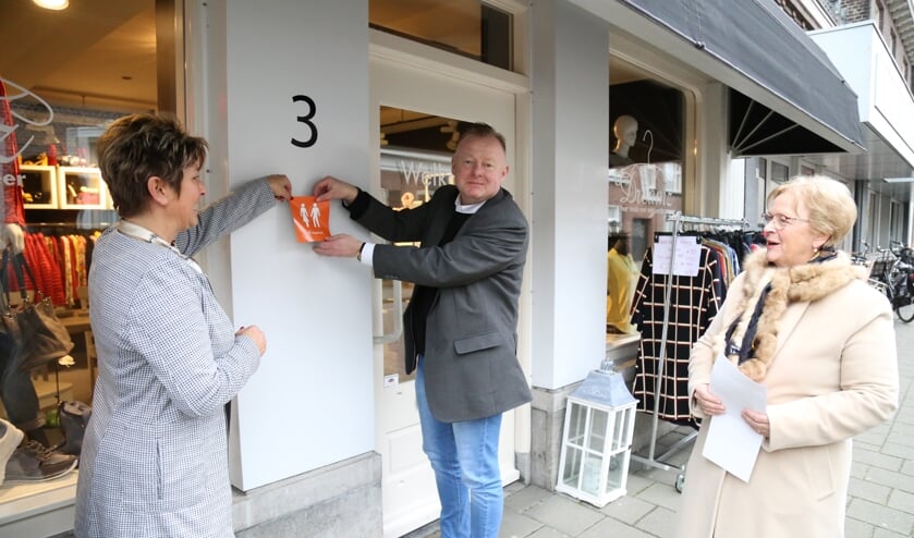 Ondernemer Petra Essen (l.), wethouder Eric van den Broek en Diny Stolvoort plakken de eerste 'Hoge Nood' sticker. | Fotonummer: b55bf9