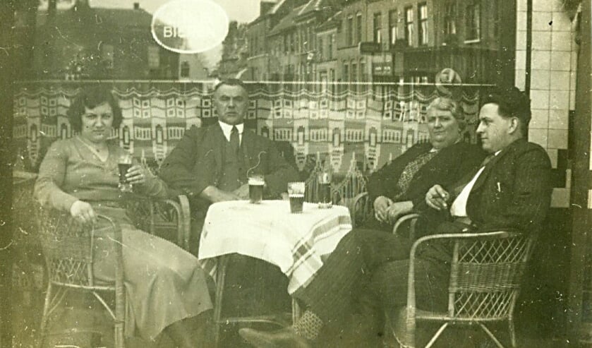 Een straatfotograaf op de Markt fotografeerde mensen die naar de Sint Petruskerk gingen of er vandaan kwamen. In de spiegeling in de etalage is oostkant van de Markt te zien (spiegelbeeld) en op de achtergrond het oude gemeentehuis dat in 1937 werd afgebroken Op de foto: Fam. Adam en Ru Verbruggen. | Fotonummer: abfffc