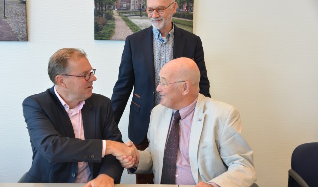 Voorzitter Jan Legierse (rechts) en wethouder Koos Krook bezegelen de overeenkomst met een handdruk. Penniingmeester Rien van Zundert kijkt toe.