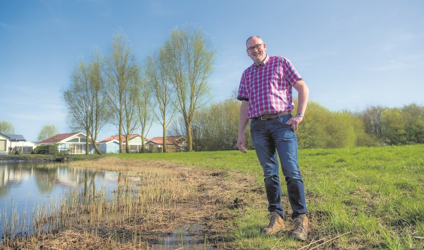 Ondernemer André van Ast met rechts het Stallands bos en achterin het chaletpark en links de plas die hij wil omvormen tot forellenvijver.