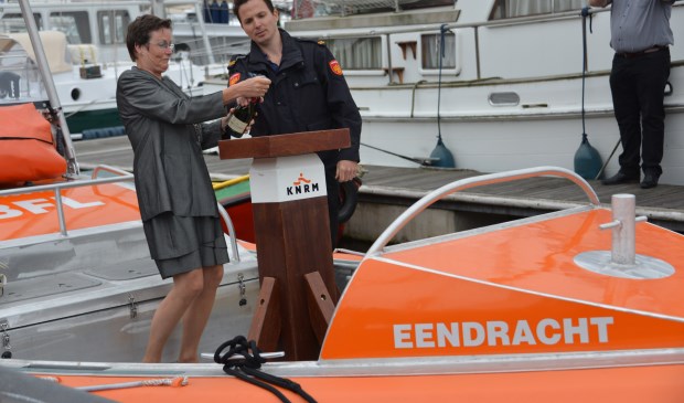 De burgemeester ontkurkt de champagne om de Eendracht te dopen.