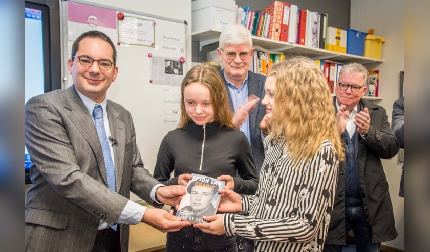 Burgemeester Adriaansen overhandigt het boek 'Spion van Oranje' aan Britt en Loïs.