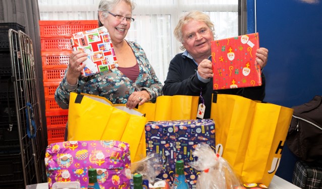 Annemarie Kissing (links), secretaris van Stichting Voedselbank Land van Cuijk, en een medewerker stoppen in Cuijk sinterklaascadeau's in de voedselpakketten. Foto: Diana Derks