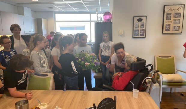 De leerlingen overhandigen de bloemen aan een bewoonster.