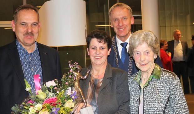 Burgemeester Roolvink (achter midden) zette vrijwilliger Jacqueline Brouwer (midden) tijdens de nieuwjaarsreceptie in het zonnetje. Echtgenoot en moeder waren met haar meegekomen. (foto: Annelies Graafsma)