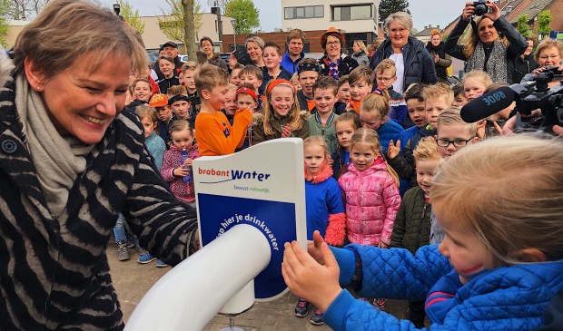 Lune (5) mocht als eerste haar bidon vullen. Wethouder Van der Pas helpt een handje.