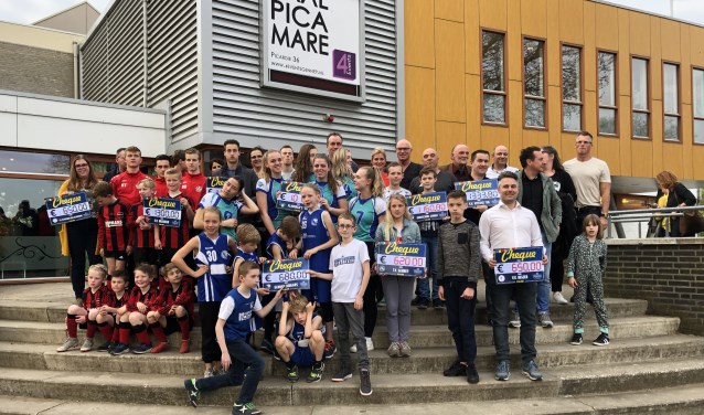 Leden van de deelnemende clubs en ondernemers tonen de cheques met de resultaten. (foto: Jos Gröniger)