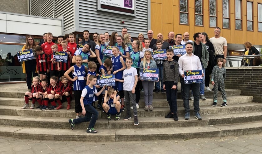 Leden van de deelnemende clubs en ondernemers tonen de cheques met de resultaten. (foto: Jos Gröniger)