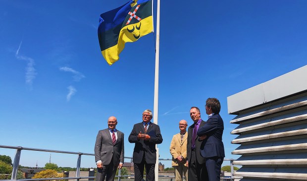 De nieuwe vlag wappert boven de hoofdrolspelers van afgelopen woensdag. Ook burgemeester Kees van Rooij (uiterst links) was aanwezig.