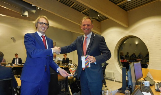 Robin Kersbergen (VVD) overhandigt na het aannemen van de motie voor een inclusieve samenleving een regenboog-stropdas aan de burgemeester
