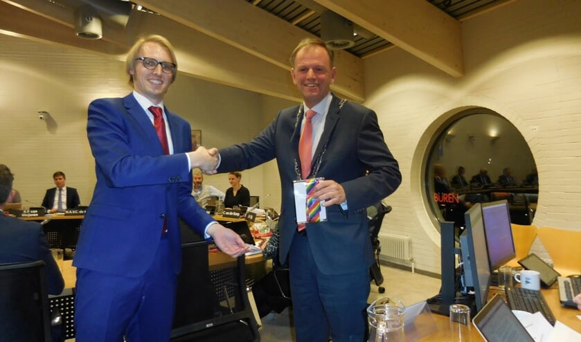 Robin Kersbergen (VVD) overhandigt na het aannemen van de motie voor een inclusieve samenleving een regenboog-stropdas aan de burgemeester