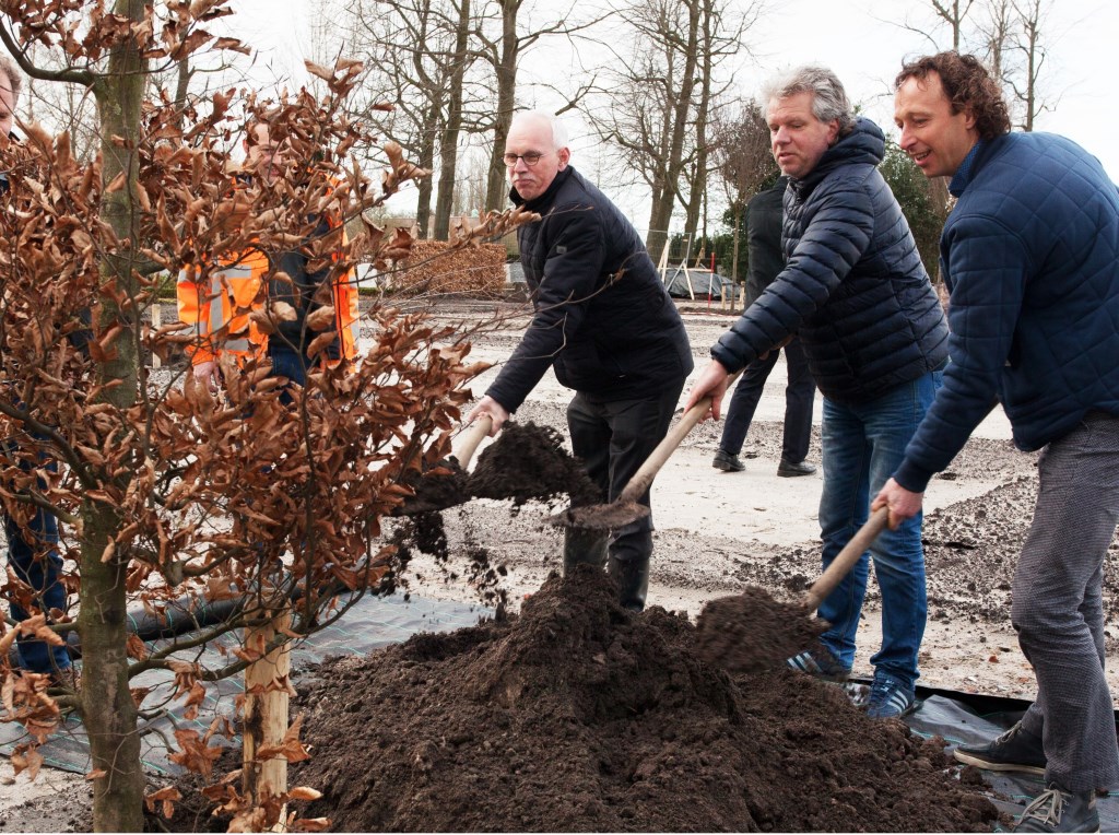Wethouder Kees Oskam plant, samen met de veretgenwoordigers van de vroegere grondeigenaren Ard Op 't Landt (rechts) en Kees Bakker, de eerste boom