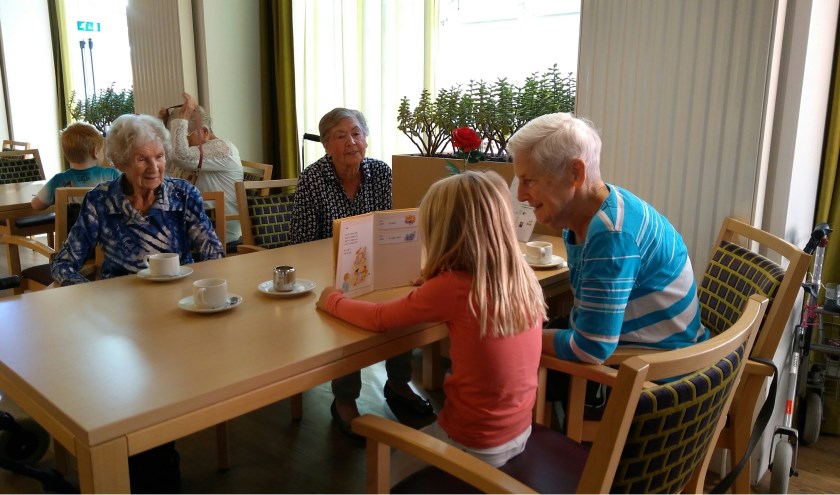 Een leerling van groep 3 van de Wilgenhoek leest voor aan een aantal bewoners in Huize St Petrus.