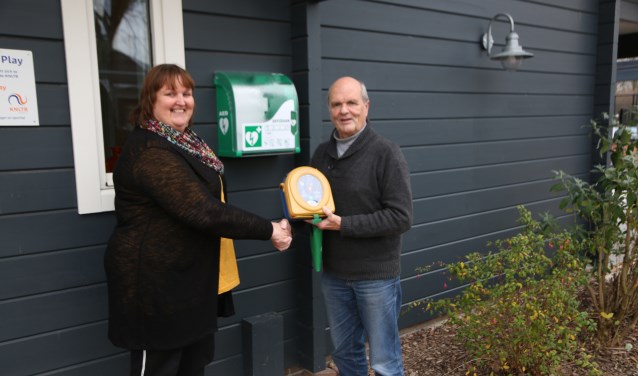 Initiatiefnemer Jacqueline de Keijser en Harry Spermon met de AED bij de nieuwe buitenkast.