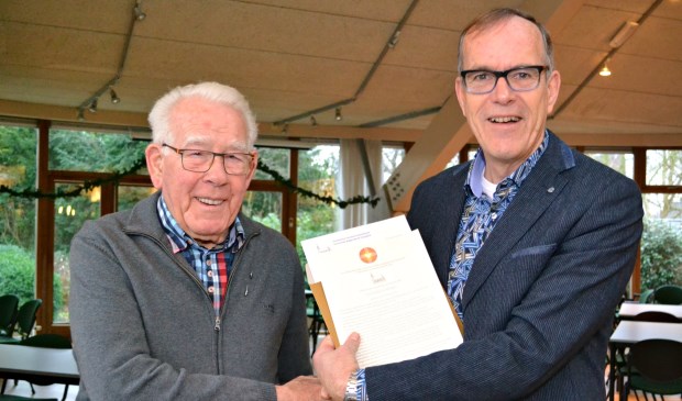 Foto: Kees Vos, voorzitter van de wijkkerkenraad, overhandigt de oorkonde aan Wim Mes.