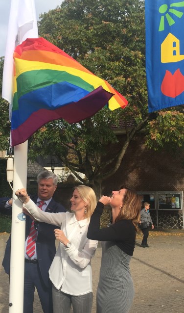 Wethouders Kees van der Zwet, Jeanet van der Laan en Jolanda Langeveld hijsen de blanco en de regenboogvlag.