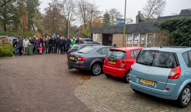 Buurtbewoners en politici bij De Menswording. De auto's geven aan tot hoever het gebouw komt dat projectontwikkelaar Pluis wil realiseren.