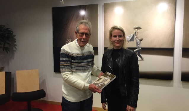 Met trots presenteert Arie zijn vierde kleine kroniek van Lisse aan wethouder Jeanet van der Laan.