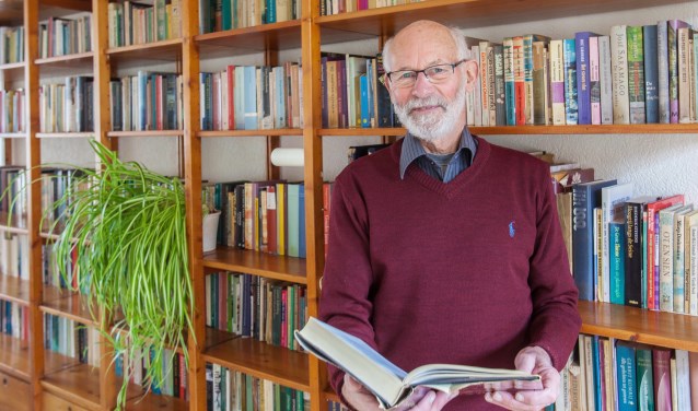 Ton Hetebrij voor de boekenkast vol verhalen. ‘Boven staan nog veel meer boeken.’ | Foto: Adrie van Duijvenvoorde.
