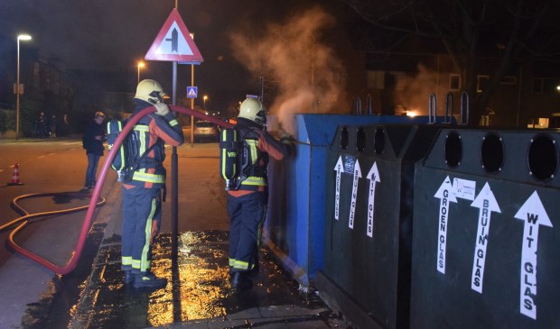 De brandweer maakt korte metten met de fik in de papiercontainer.