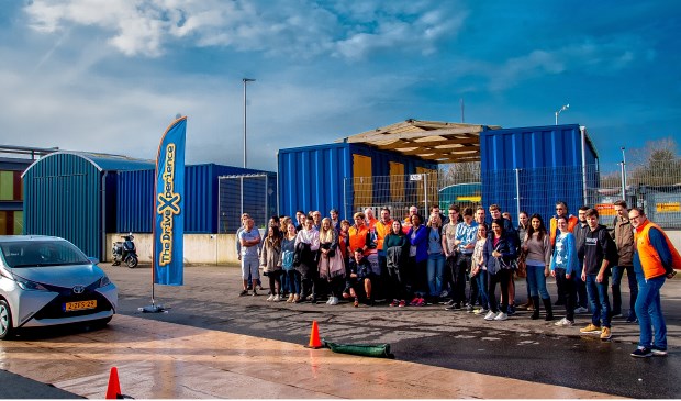 De groep deelnemers en coaches kijken toe hoe wethouder Kees Wassenaar een noodstop maakt op de slipbaan.