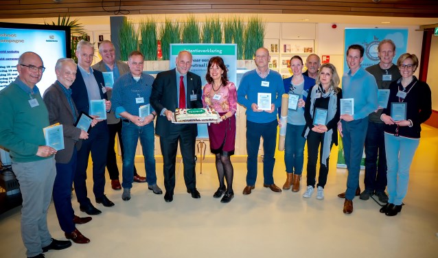 Dertien van de EA's met hun certificaten. Wethouder McDaniel staat al klaar met de taart. Tweede en derde van links staan Patrick Ploeg en Richard Hilhorst, EA's van 't Heerlijk Recht. | Foto: Johan Kranenburg
