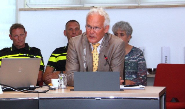 Burgemeester Rijpstra legt in de raadsvergadering een verklaring af over de noodverordening. Links politiechef Henk Woppenkamp. | Foto: WS