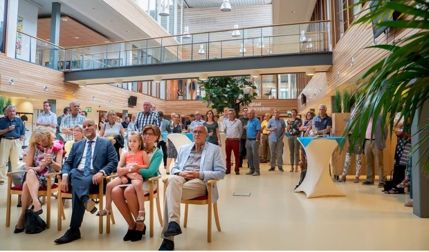 De oud-wethouders en hun echtgenoten - en kleinkind van Kees Wassenaar - luisteren naar de toespraak van burgemeester Driessen.