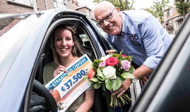 Liesbeth wordt verrast door Postcode Loterij-ambassadeur Gaston Starreveld met de PostcodeStraatprijs-cheque en de BMW. | Foto Jurgen Jacob Lodder