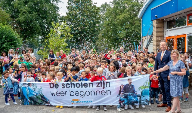 Allemaal bellen blazen om aandacht te vragen voor de campagne 'De scholen zijn weer begonnen'. Rechts naast het spandoek staat wethouder Willem Joosten.