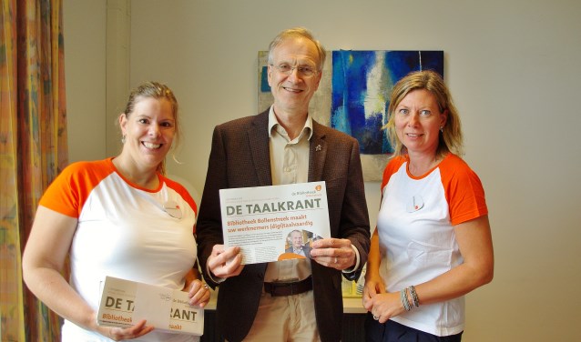 Eline de Visser (Projectleider Taalhuis) en Dionne Dinkhuijsen (programmamanager van de Bibliotheek Bollenstreek) bieden de Taalkrant aan aan wethouder Jan Nieuwenhuis. | Foto Willemien Timmers