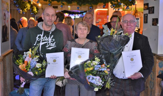 Roland, Ineke en Bert met bloemen en de waarderingsspeld voor hun vrijwilligerswerk.