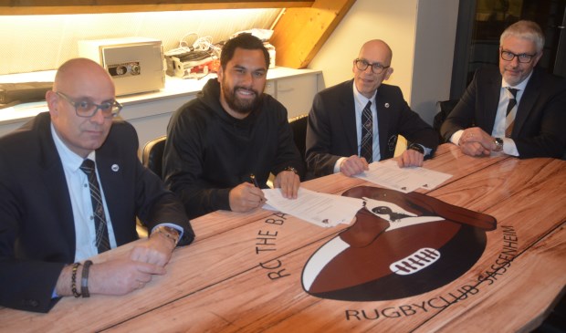 Storm Carroll tekent het contract in Sassenheim, onder toeziend oog van het Bassets-bestuur.