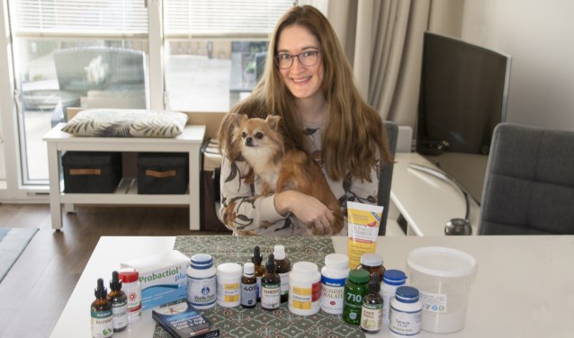 Mariëlle met haar hondje Benthe, te midden van alle supplementen die ze nodig heeft.