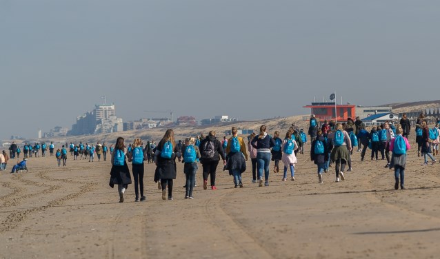 De kinderen wandelen deels over strand.