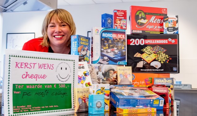 Adinda Dernison met een deel van de nieuwe spellen. Links de cheque die de Vrienden van het Oude Dorp vlak voor kerst uitreikten.
