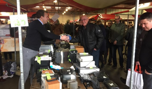 Een tevreden bezoeker doet een goede koop bij een van de vele kramen van de snuffelmarkt.
